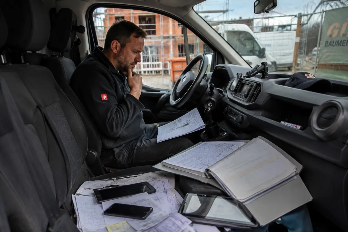Bauleiter prüft Dokumente und Baustelleninformationen zur besseren Kommunikation und Organisation